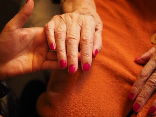 Yaşlı bir kadının eline oje sürüyorum. 