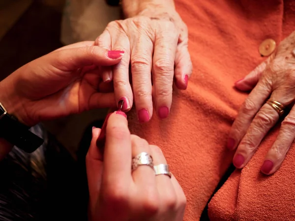 Yaşlı bir kadının eline oje sürüyorum.