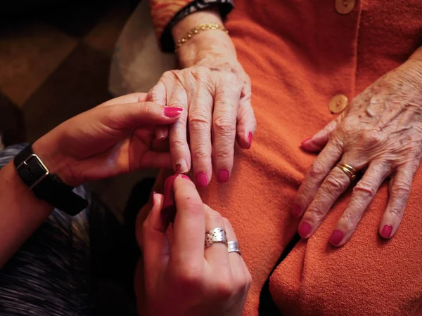 Yaşlı bir kadının eline oje sürüyorum.