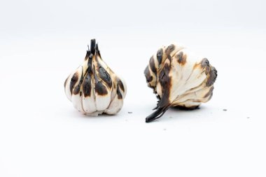 Beyaz arka planda kavrulmuş sarımsak karanfilleri ve ampul..