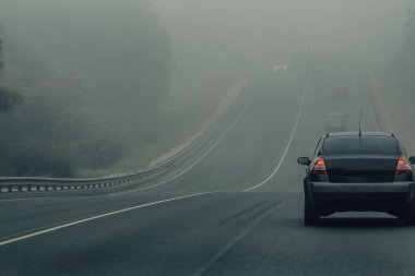 Tehlikeli havada otoyolda sis içinde giden arabalar. Düşük görüş mesafesi ve otomobil trafiği kötü. Otobanda puslu araçlar
