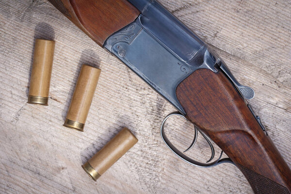 Shotgun forearm with two triggers top view. Rifle charges or cartridges on a wooden surface. Hunting theme, male hobby