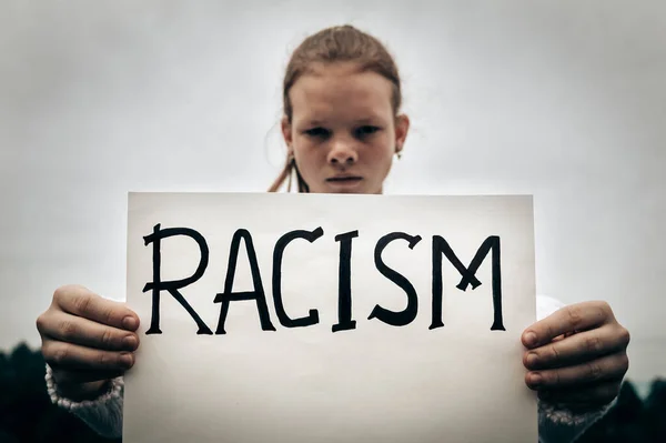 Jovem adolescente menina segura cartaz com palavra Racismo. Parem com a discriminação e a desigualdade étnica. Protesto ativista irritado. Direito de observância — Fotografia de Stock