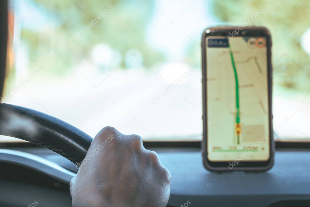 Map on smartphone of car dashboard. Mobile phone with gps or glonass navigation. Driver hand holds steering wheel