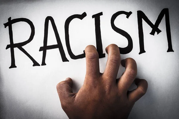 African child hand scratches word racism. No to racism. Hate of ethnic prejudice. Concept of equality — Stock Photo, Image