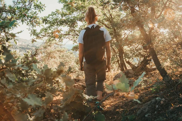 Giovane ragazza con zaino cammina attraverso i boschi in terreno montagnoso. Viaggi nel fine settimana, stili di vita attivi. Escursioni e avventura selvaggia — Foto Stock