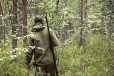 Avcı av tüfeğiyle ormanda yürüyor. Av sezonu. Fowling parçası. Vahşi doğa arka planı