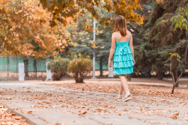 Happy girl playfully walks along autumn street in good mood. Dancing young woman in turquoise dress with beautiful legs. Freedom — Stock Photo, Image