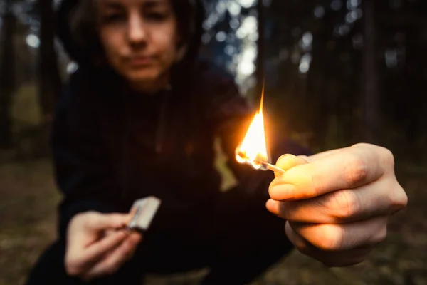 Woman rebel with burning match in hands in dark. Riot or revolution, civil protest. Danger of arson. Flame in hands of bully