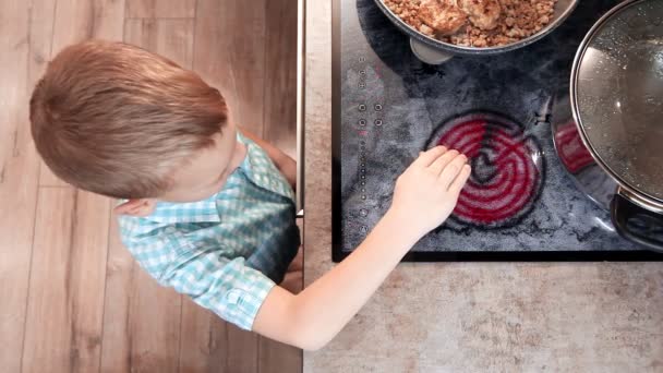 Nysgjerrige barn leker på kjøkkenet med varm elektrisk ovn. Risiko for å brenne barn hjemme. Husholdningsfare – stockvideo