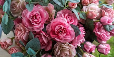 Taze kahve dükkanlarında pembe plastik güller (Rosa melezleri). Müşteriler için fotoğraf çekmek için köşeyi dekore et.