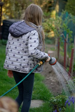 Kız baharda bahçeyi sular.