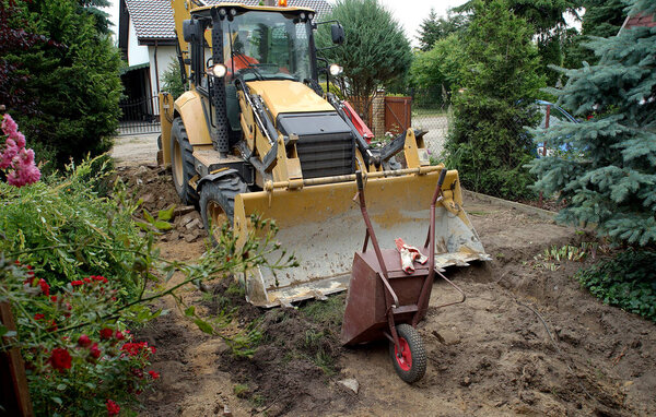 экскаватор и тачка на строительной площадке в сельской местности
