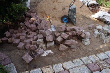 Kırmızı granit yığını kaldırım taşları ve el arabası.