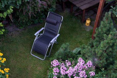 Ev bahçesinin çimenliğinde duran bir iskemlenin üst görüntüsü.