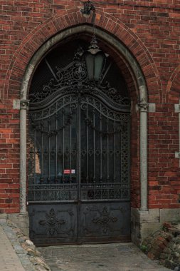 Kara metal entrika kapıları, kırmızı tuğla kilise binasının kapısı, fener ışığı.