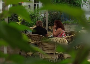 Riga, Letonya - 29 Haziran 2020: Eski bir açık hava kafesi, iki kadın turist kilitli kaldıktan sonra eğleniyor, paparazi tarzı fotoğraf.