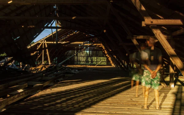 Eski bir çiftlik binası çatısı ayakta duran bir hayalet ahşap zeminde güneş ışığı ve kırık bir çatı.