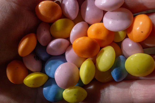 Bir sürü küçük renkli yuvarlak şeker ellerinde