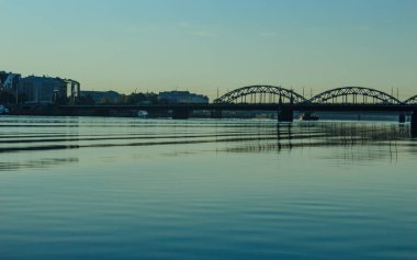 Riga, Letonya - 17 Temmuz 2020: Başkent mimari binaları gün doğumunda görünür, nehir suyu renkleri