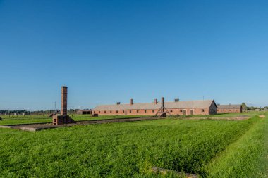Auschwitz, Polonya, 6 Ağustos 2025. Auschwitz Birkenau Toplama ve İmha Kampı giriş kapısının önünde bacalar var.
