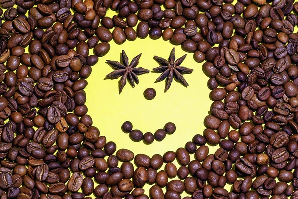 Smiling face made of coffee beans and anise.