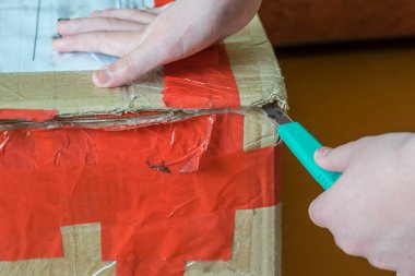 Karton kutuları kesiciyle açan adam.