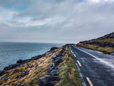 Arka planda Atlantik Okyanusu olan kıyı manzaralı bir yol soğuk bir kış gününde