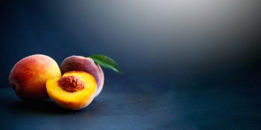 Taze şeftaliler ve siyah arka planda yapraklarla bölünmüş. Sancak konsepti.