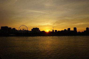 Gün batımında Montreal Old Port ve Downtown 'ın ufuk çizgisi. Ön plan Saint Laurent nehri..