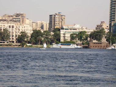 Güneşli bir yaz gününde modern binaların arka planına sahip nehir Nil kıyısı ve yelkenli tekneleri, Kahire, Mısır