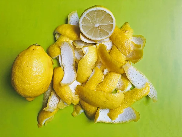 Yellow and white lemon peel on a light green background. Nearby lies a whole lemon and half a lemon. Cooking Limoncello. Ingredients for Lemonade.