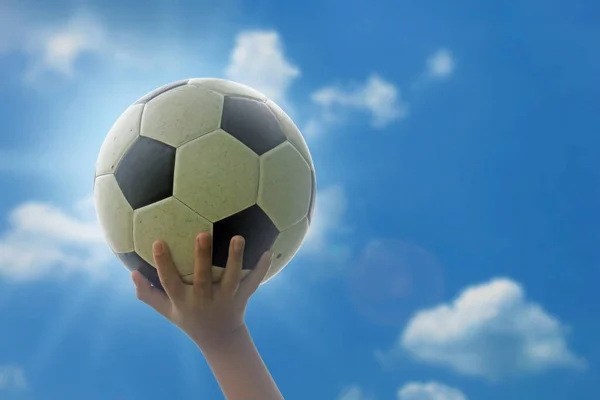 Çocuk futbol topunu başının üzerinde tutuyor. Gökyüzünün parlak ve parlak arka planında kırpma yolu ile.