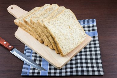 Dilimlenmiş buğday ekmeği Doğranmış Odun ve masa örtüsü arka planı, seçici odaklanma.