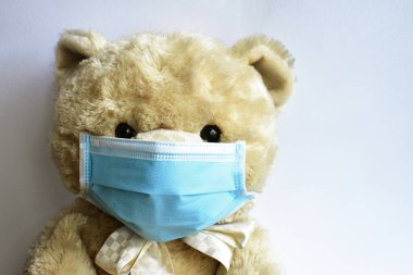Beyaz arka planda mavi tıbbi maskeli sevimli kahverengi ayı. Doktor ayı yüz maskesi takıyor. Hastalık virüsü yaymaya karşı koruyucu. CoV-2 Corona virüsü.