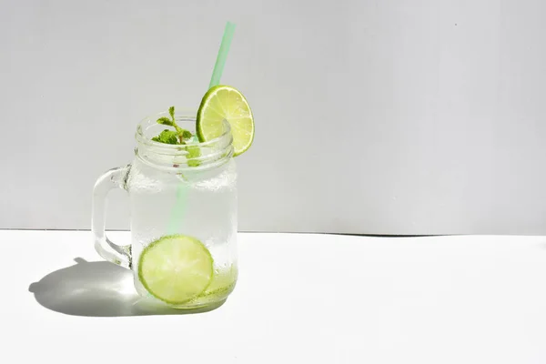 緑のレモンスライスとミントの葉を持つレモネードのメイソン瓶ガラス 白の背景に隔離された蜂蜜 夏のドリンク 新鮮な 自家製 クール フルーツジュース サイドビュー — ストック写真