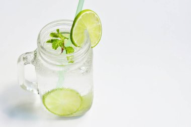 Yeşil limon dilimi ve nane yaprağı ile Mason kavanozu bardağı limonata, beyaz arka planda izole edilmiş bal, yaz içeceği, taze içecek, ev yapımı, soğuk, meyve suyu, yan görüş