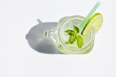 Yeşil limon dilimi ve nane yaprağı ile Mason kavanozu bardağı limonata, beyaz arka planda izole edilmiş bal, yaz içeceği, taze içecek, ev yapımı, soğuk, meyve suyu, yan görüş