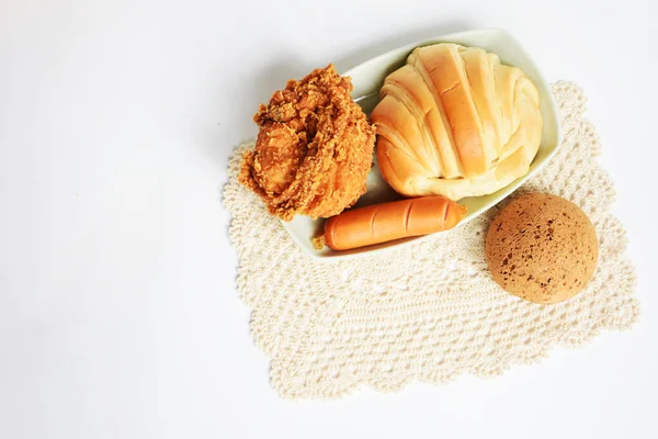 Beautiful, delicious breakfast table, dish of sweet croissant, Korean sesame Mochi bread or Japanese Mochi bun, fried chicken, pig sausage white background, bakery,  junk food, fast food