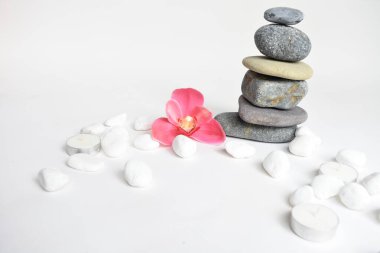 Beyaz arka planda izole edilmiş taş yığınları ve pembe orkide çiçeği. Çakıl taşı kulesi. Denge ve uyum kavramı. Sakin ve ruh, spa taşları ve zen, barış, meditasyon, manevi ve soyut