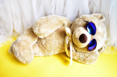 Tatlı oyuncak ayıcık kumsalda yatıyor, sarı ve beyaz şifon arka plan, rahatla, yaz tatili, çocuk oyuncağı, çocukluk anısı