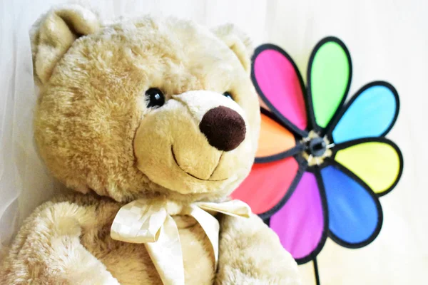 Cute teddy bear soft toy holding a rainbow pinwheel/ windmill, kids toys, childhood memory, vintage background