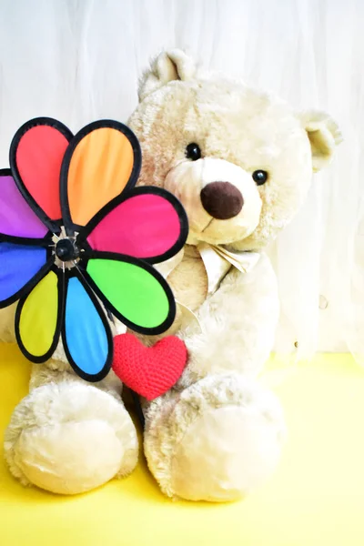 Cute teddy bear soft toy holding a rainbow pinwheel/ windmill, kids toys, childhood memory, vintage background