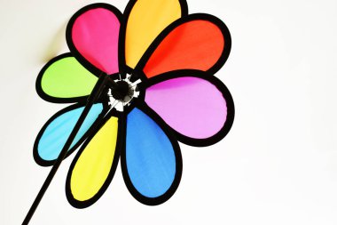 Beyaz arka planda gökkuşağı renginde çiçeklerle izole edilmiş fırıldak, çocukluk oyuncağı, yel değirmeni, çocuk hediyesi