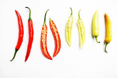 Kırmızı biber, yeşil kırmızı biber dilimleri / beyaz arka planda yarı izole edilmiş, deri döşeme, üst manzara, beyaz masada Tayland biberi.