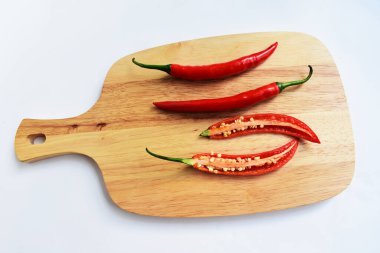 Kırmızı ve yeşil kırmızı kırmızı biber dilimleri / yarısı ahşap kesim tahtasından izole edilmiş beyaz arka plan, deri döşeme, üst manzara, Tayland biberi beyaz masa