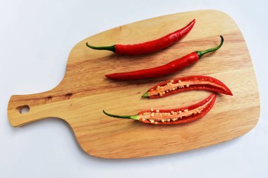 Kırmızı ve yeşil kırmızı kırmızı biber dilimleri / yarısı ahşap kesim tahtasından izole edilmiş beyaz arka plan, deri döşeme, üst manzara, Tayland biberi beyaz masa