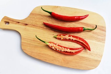 Kırmızı ve yeşil kırmızı kırmızı biber dilimleri / yarısı ahşap kesim tahtasından izole edilmiş beyaz arka plan, deri döşeme, üst manzara, Tayland biberi beyaz masa