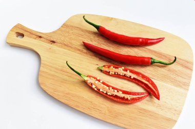 Kırmızı ve yeşil kırmızı kırmızı biber dilimleri / yarısı ahşap kesim tahtasından izole edilmiş beyaz arka plan, deri döşeme, üst manzara, Tayland biberi beyaz masa