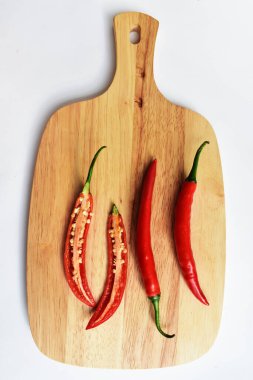 Kırmızı ve yeşil kırmızı kırmızı biber dilimleri / yarısı ahşap kesim tahtasından izole edilmiş beyaz arka plan, deri döşeme, üst manzara, Tayland biberi beyaz masa